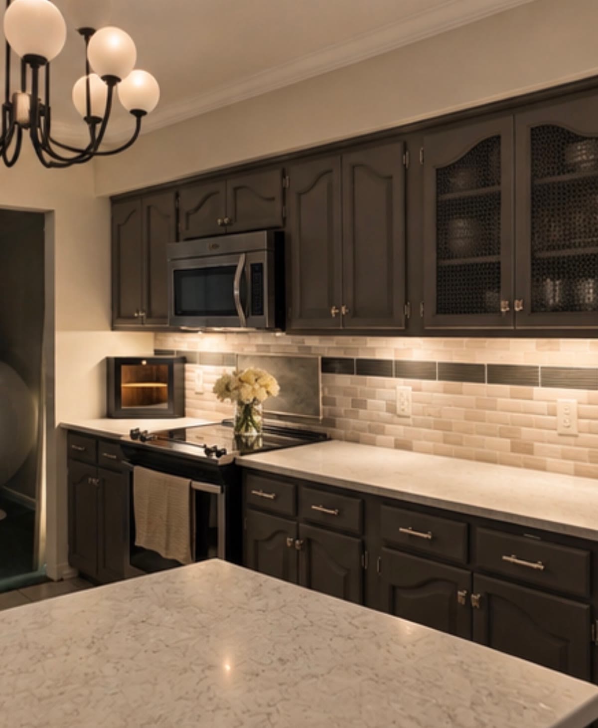 Kitchen with dark cabinets, quartz counters, and under-cabinet lighting