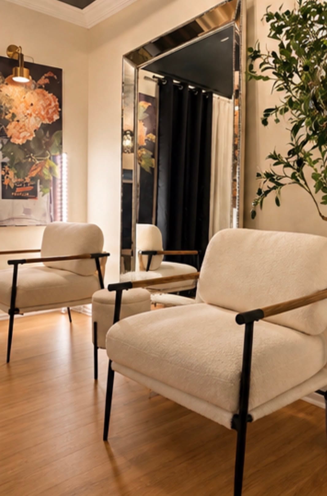Bright sitting area with cream lounge chairs and a large floor mirror